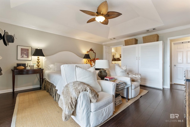 bedroom with a tray ceiling, crown molding, dark hardwood / wood-style floors, and ceiling fan