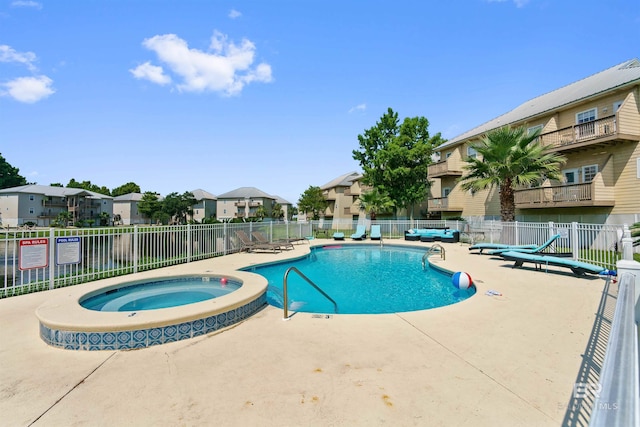 pool featuring a community hot tub, a patio area, a residential view, and fence