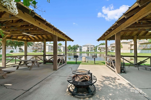 view of property's community with an outdoor fire pit, a water view, a residential view, and a gazebo