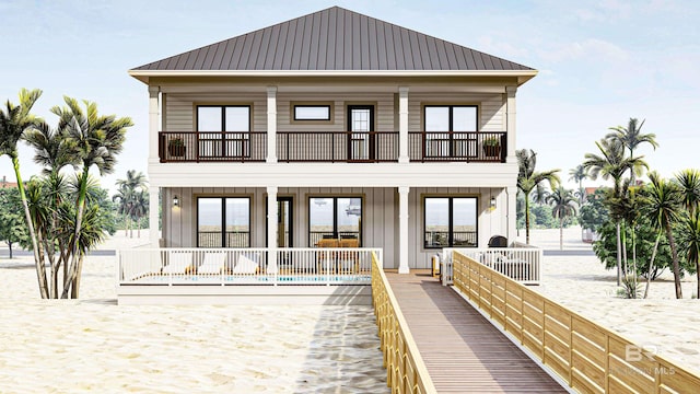 rear view of house with a balcony, a pool, metal roof, and board and batten siding