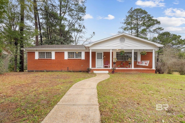 view of front of property featuring a front yard, a porch, and brick siding