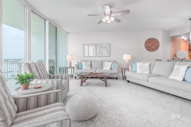 living room with ceiling fan with notable chandelier and a wall of windows