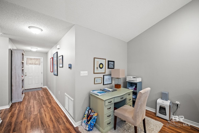 office space with baseboards, a textured ceiling, visible vents, and wood finished floors