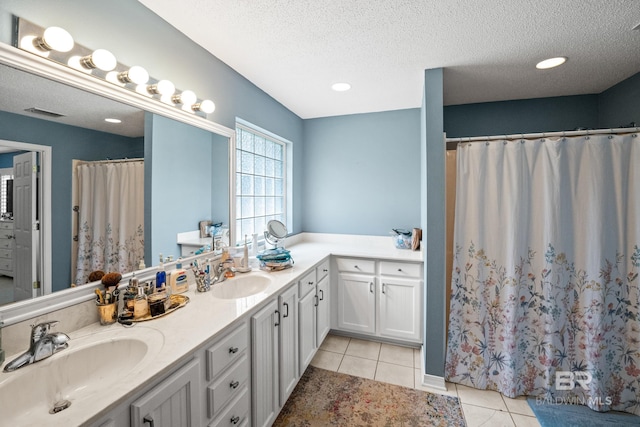 bathroom featuring tile patterned flooring, a sink, and a textured ceiling