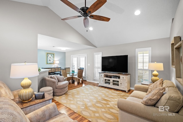 living area with high vaulted ceiling, a healthy amount of sunlight, baseboards, and wood finished floors