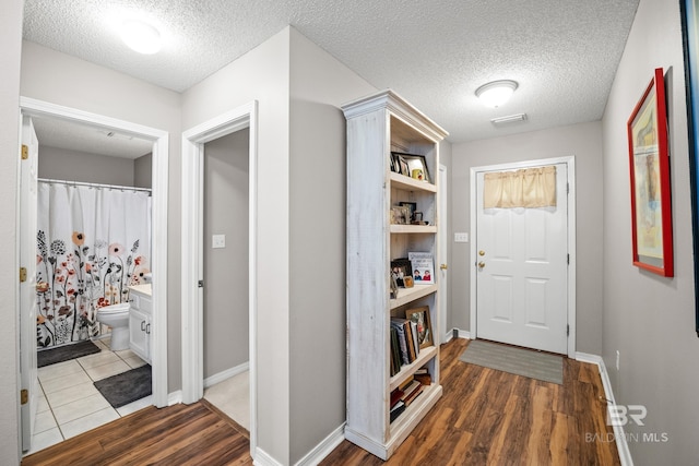 entryway featuring a textured ceiling, wood finished floors, and baseboards