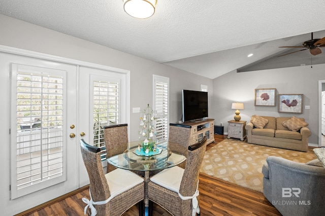 dining space with ceiling fan, a textured ceiling, wood finished floors, vaulted ceiling, and french doors