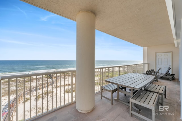balcony with view of water and beach and outdoor dining area