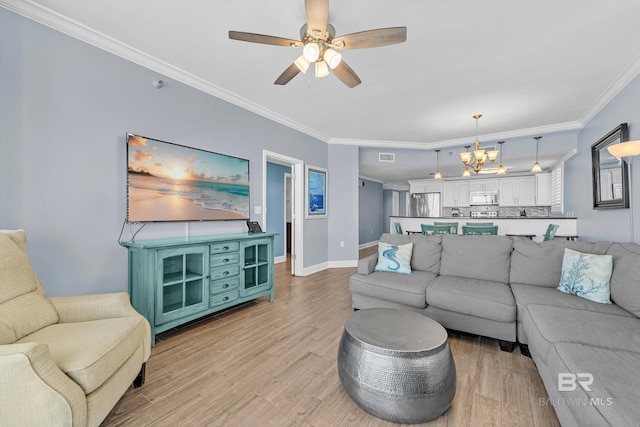 living room featuring a chandelier, ornamental molding, light wood-style floors, a ceiling fan, and baseboards