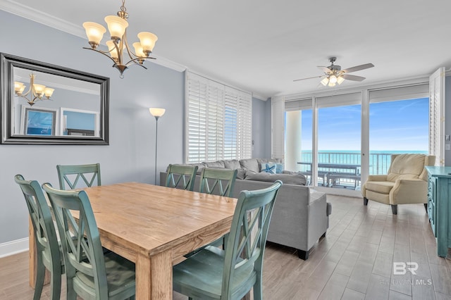 dining room with a chandelier, a water view, ornamental molding, a ceiling fan, and light wood-style flooring