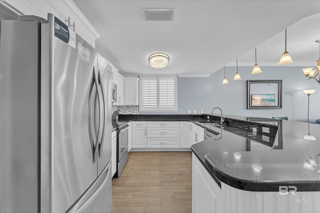 kitchen with appliances with stainless steel finishes, a sink, light wood-type flooring, white cabinets, and ornamental molding