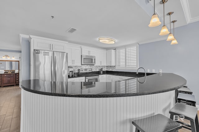 kitchen featuring stainless steel appliances, a peninsula, white cabinetry, pendant lighting, and light wood-style flooring