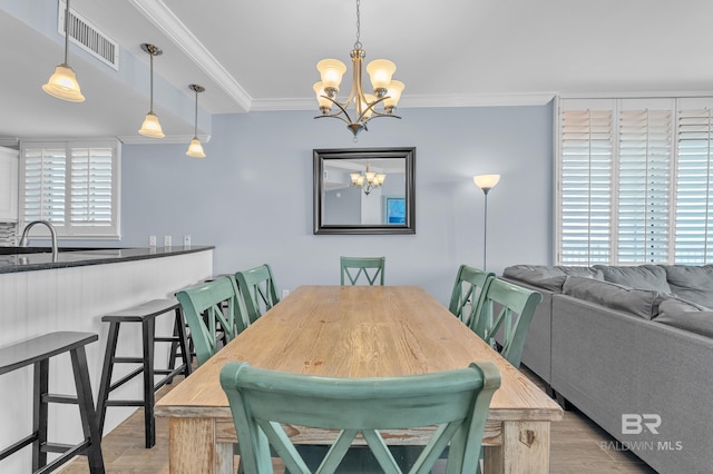 dining space featuring a chandelier, light wood-style floors, and crown molding