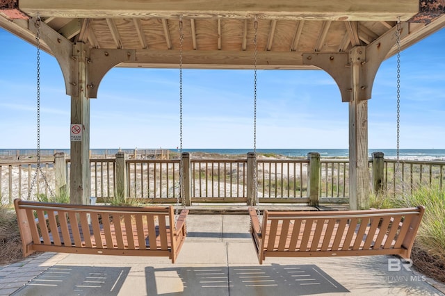 deck featuring view of water and beach and a gazebo