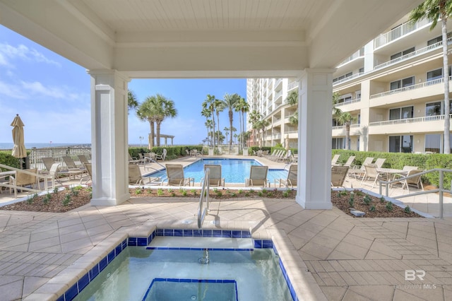 community pool with a hot tub and a patio area