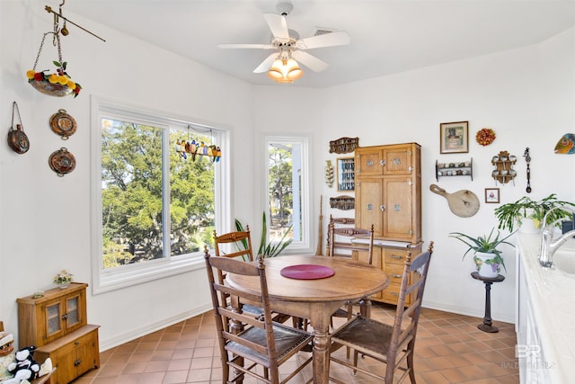 tiled dining space featuring a ceiling fan and baseboards