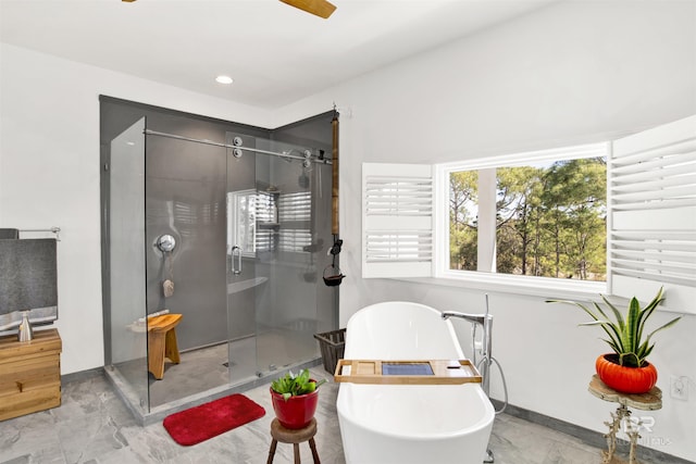 bathroom featuring marble finish floor, a stall shower, a freestanding tub, and recessed lighting