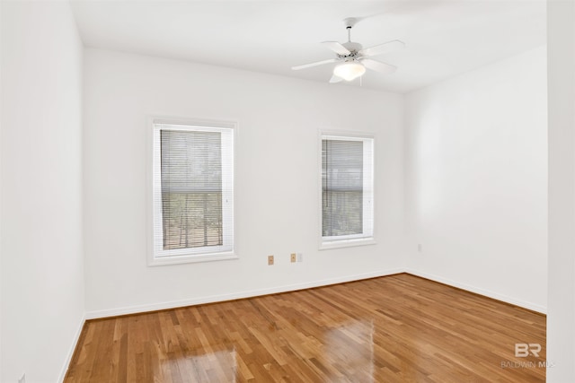 spare room with a ceiling fan, light wood-type flooring, plenty of natural light, and baseboards