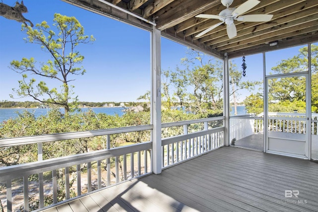 unfurnished sunroom featuring a water view and a ceiling fan