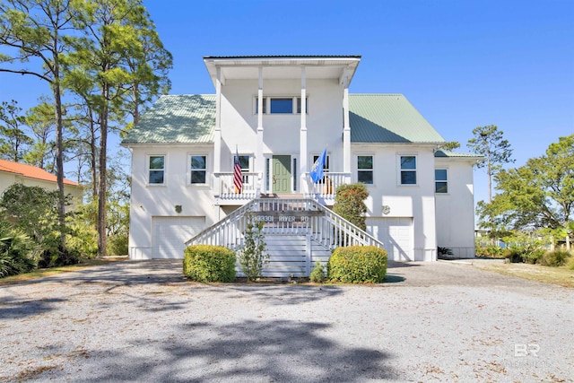 view of front of house featuring a garage, covered porch, stairway, and metal roof