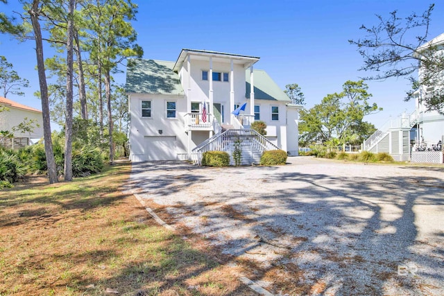 view of front of house featuring a porch, a garage, stairs, driveway, and stucco siding