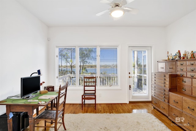 office space with baseboards, a ceiling fan, and light wood-style floors