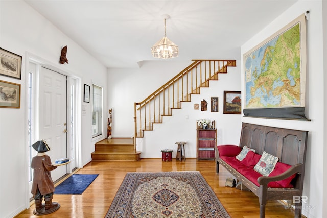 entrance foyer featuring an inviting chandelier, stairs, and wood finished floors