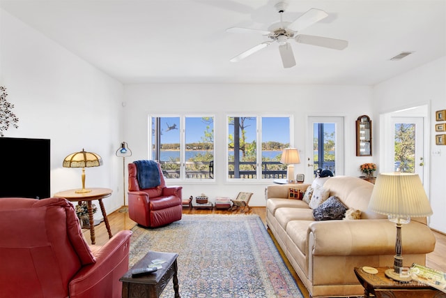 living area with ceiling fan, visible vents, and wood finished floors