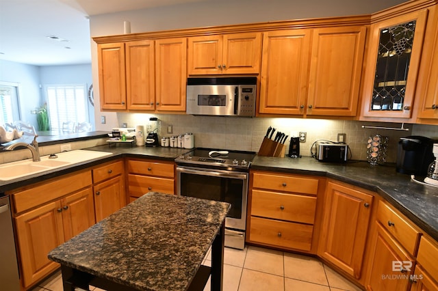 9397 S Bay Rd, Foley, AL 36535 - kitchen with brown cabinets, backsplash, light tile patterned floors, and appliances with stainless steel finishes