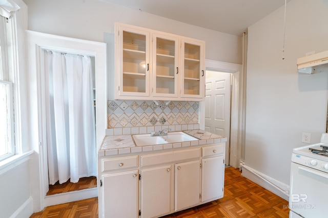 kitchen with tasteful backsplash, sink, white range, tile counters, and white cabinets