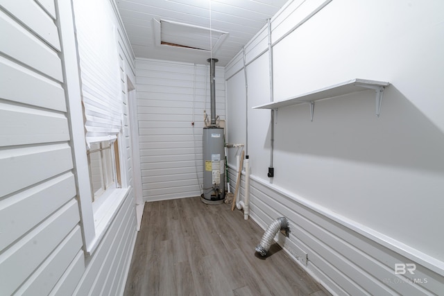 laundry area featuring light hardwood / wood-style floors, wood walls, and gas water heater