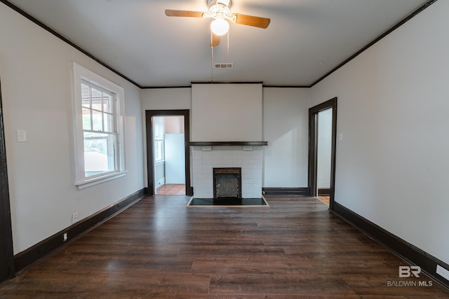 unfurnished living room with dark wood-type flooring, ceiling fan, ornamental molding, and a brick fireplace