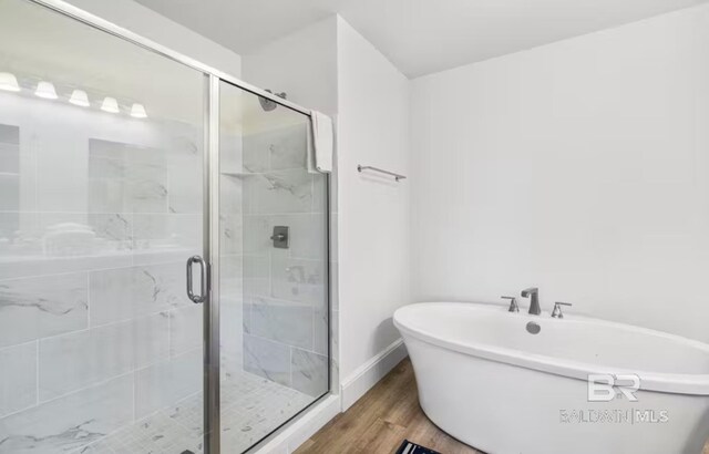 27070 Perdido Beach Blvd Unit 10W, Orange Beach, AL 36561 - full bathroom featuring a shower stall, baseboards, wood finished floors, and a freestanding tub