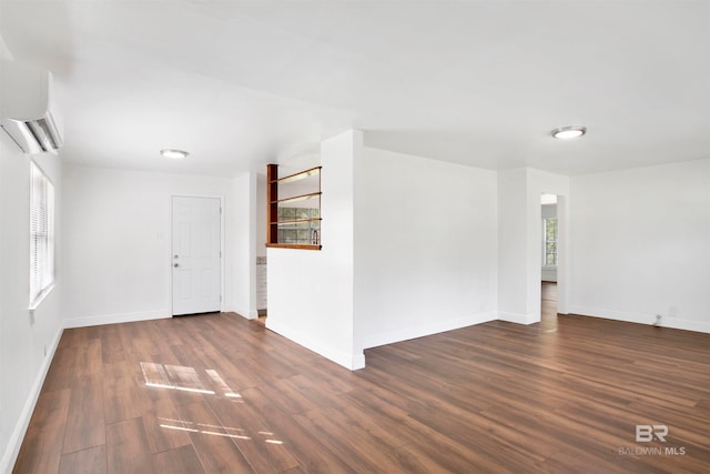 spare room with a wall unit AC and dark hardwood / wood-style floors