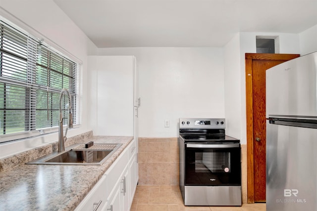 kitchen featuring white cabinetry, stainless steel appliances, sink, and light tile patterned flooring