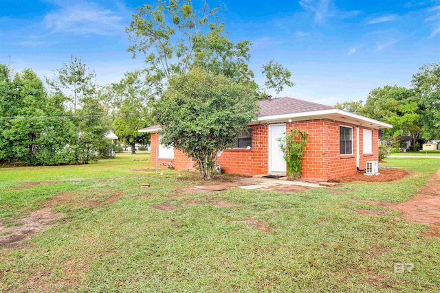 view of side of property featuring a lawn and central AC