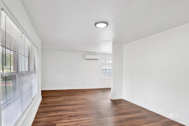 unfurnished room with dark hardwood / wood-style flooring and an AC wall unit