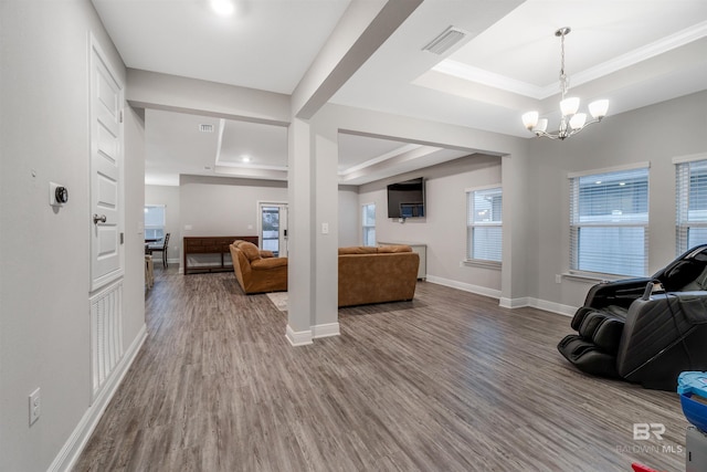 living room featuring hardwood / wood-style floors, an inviting chandelier, and a tray ceiling