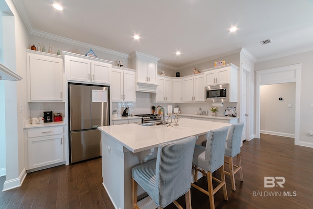 kitchen featuring stainless steel appliances, sink, white cabinets, dark hardwood / wood-style floors, and an island with sink