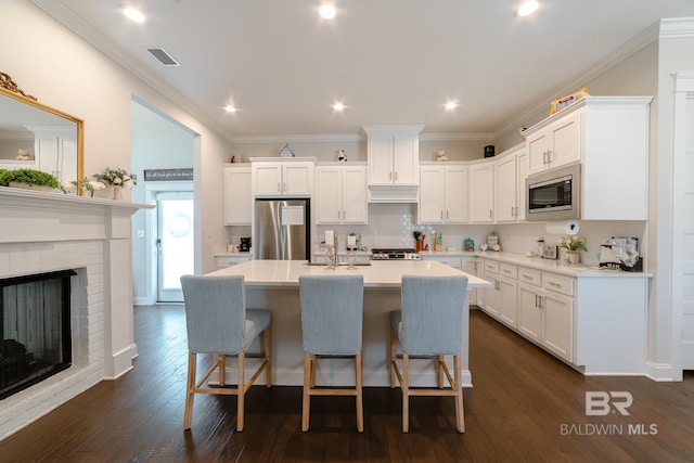 kitchen with dark hardwood / wood-style flooring, stainless steel appliances, white cabinetry, and a kitchen island with sink