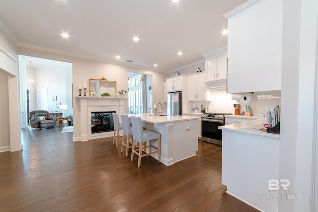 kitchen with a breakfast bar, a center island, dark wood-type flooring, white cabinets, and appliances with stainless steel finishes