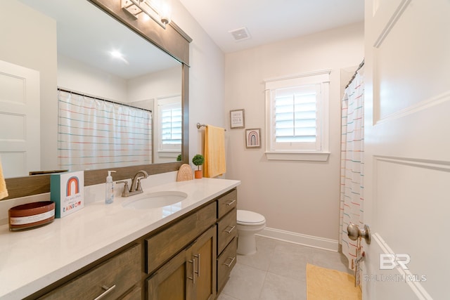 bathroom with tile patterned flooring, vanity, toilet, and a wealth of natural light