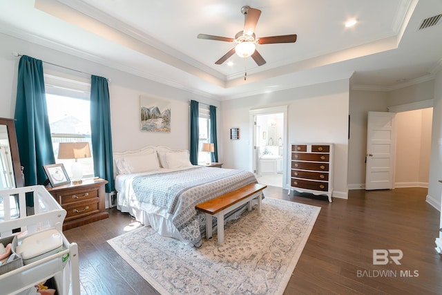 bedroom featuring dark hardwood / wood-style flooring, ensuite bath, a raised ceiling, ceiling fan, and crown molding