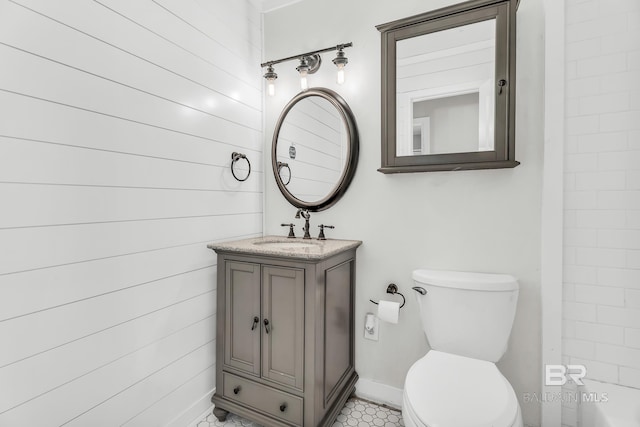 bathroom featuring vanity, wooden walls, and toilet