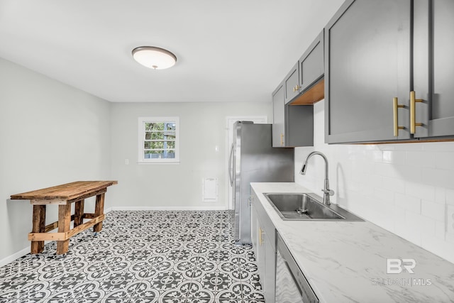 kitchen with gray cabinets, appliances with stainless steel finishes, backsplash, and sink