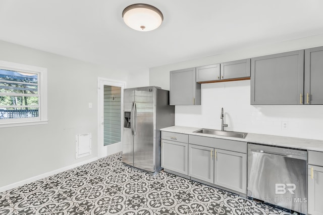 kitchen featuring gray cabinetry, stainless steel appliances, light tile patterned floors, and sink