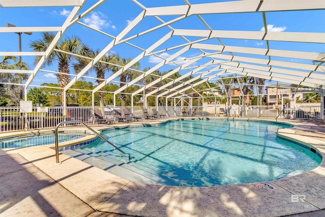 community pool with a patio, glass enclosure, and fence