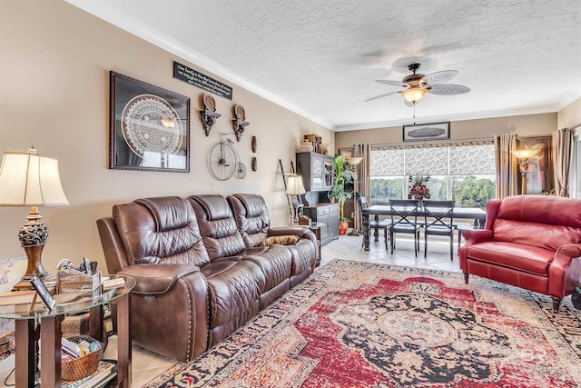 tiled living area with a ceiling fan, a textured ceiling, and ornamental molding