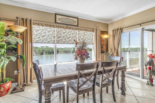 dining area with ornamental molding, a textured ceiling, a water view, and light tile patterned floors
