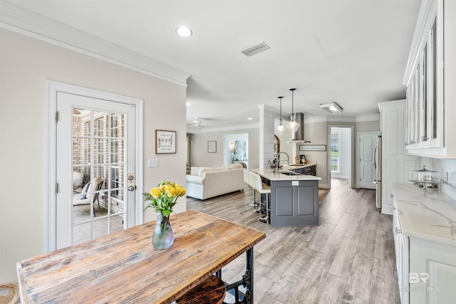 dining area with crown molding, light hardwood / wood-style flooring, sink, and ceiling fan